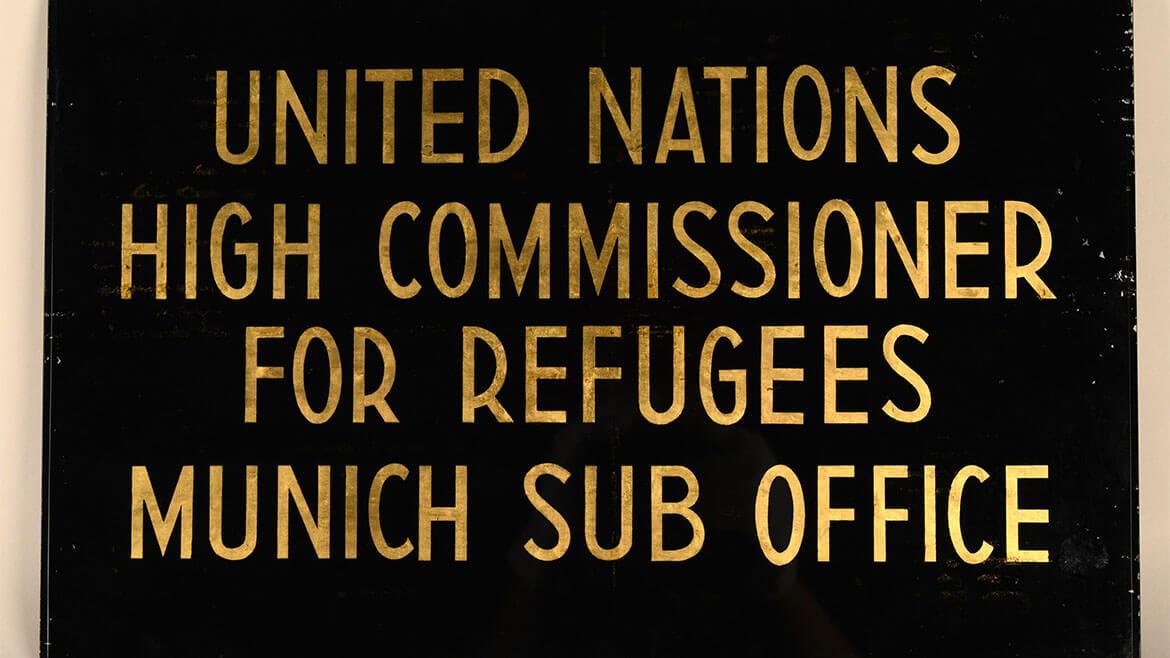 Türschild des ersten UNHCR-Büros in Deutschland nach 1951: Der Flüchtlingskommissar der Vereinten Nationen (UNHCR) ist nach dem Zweiten Weltkrieg zunächst für "Displaced Persons" in Deutschland zuständig. So werden offiziell ehemalige Zwangsarbeiter*innen und Häftlinge und genannt, die das Konzentrationslager überlebt haben und sich außerhalb ihrer Heimatländer befinden.