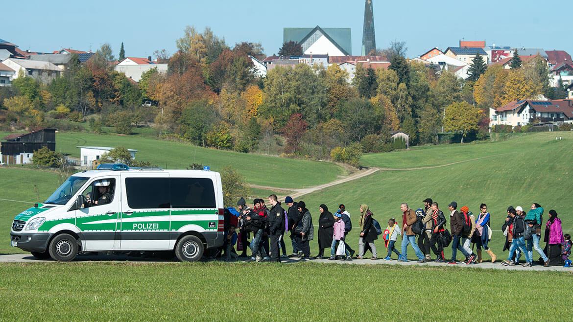 Flüchtlinge bei ihrer Ankunft in Deutschland, 2015: In den letzten Jahren kamen zahlreiche Flüchtlinge aus Kriegs- und Krisengebieten wie Syrien, Eritrea und Afghanistan nach Deutschland. Das Foto zeigt Asylsuchende, die nach ihrer Ankunft Ende Oktober 2015 von der Polizei zu einer Notunterkunft in der Nähe von Wegscheid in Bayern begleitet werden.