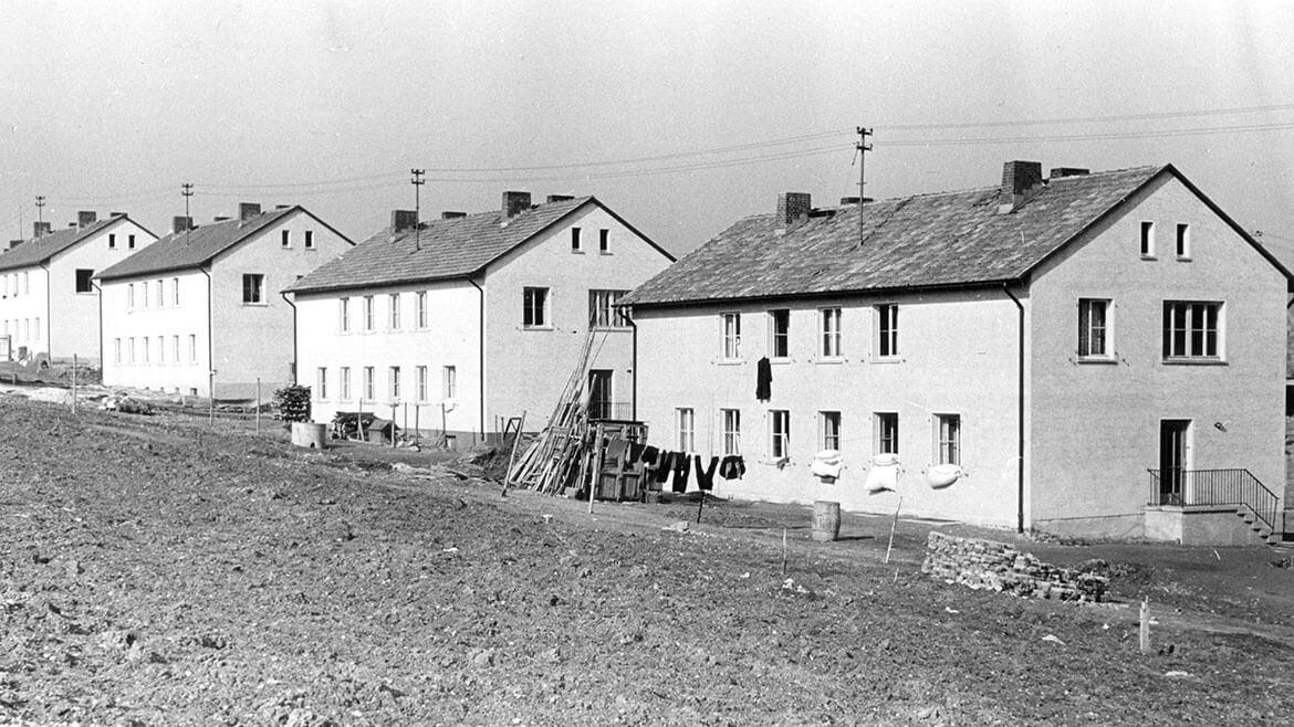 Siedlung Bleidenstadt in Taunusstein, 1952: Millionen von Flüchtlingen und Vertriebenen mussten in der Nachkriegszeit zunächst mit provisorischem Wohnraum versorgt werden. Einquartierung in Privathaushalten oder Unterbringung in Lagern sollten keine langfristige Lösung sein. Deshalb wurden in Westdeutschland seit den 1950er Jahren vielerorts Siedlungen errichtet, in denen die Heimatlosen ein neues Zuhause fanden. Siedlung Bleidenstadt in Taunusstein, 1952: Millionen von Flüchtlingen und Vertriebenen mussten in der Nachkriegszeit zunächst mit provisorischem Wohnraum versorgt werden. Einquartierung in Privathaushalten oder Unterbringung in Lagern sollten keine langfristige Lösung sein. Deshalb wurden in Westdeutschland seit den 1950er Jahren vielerorts Siedlungen errichtet, in denen die Heimatlosen ein neues Zuhause fanden.