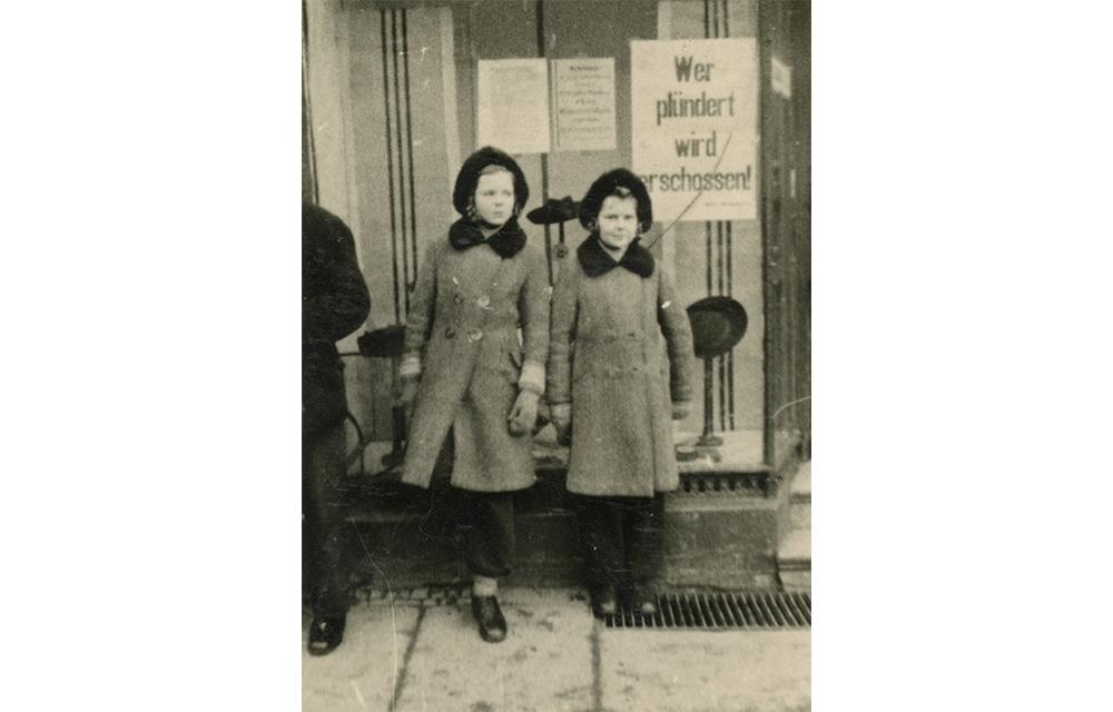 Da die Mutter für das Festhalten der ersten Lebensmonate ihres dritten Kindes eine Kamera mitgenommen hatte, hielt sie zusätzlich Momente ihrer Flucht fest, indem sie ihre Töchter, wie hier in Primkenau im Januar 1945, vor Motiven platzierte, die sonst nicht hätten fotografiert werden dürfen. Da die Mutter für das Festhalten der ersten Lebensmonate ihres dritten Kindes eine Kamera mitgenommen hatte, hielt sie zusätzlich Momente ihrer Flucht fest, indem sie ihre Töchter, wie hier in Primkenau im Januar 1945, vor Motiven platzierte, die sonst nicht hätten fotografiert werden dürfen.