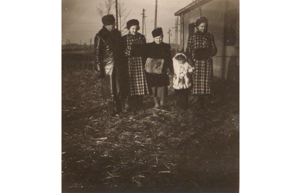 Die Familie zeigt sich hier in ihren neu erworbenen Mänteln im Winter 1949/50. Sie stehen neben ihrer umgebauten Baracke, in der sie ab Dezember 1947 leben.