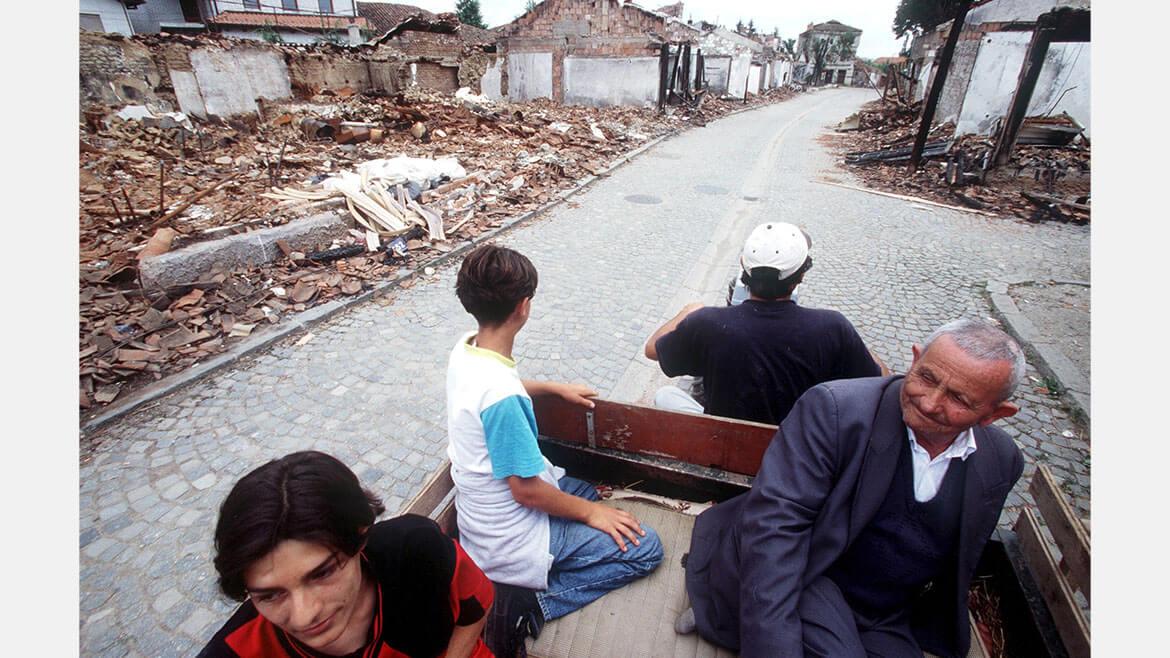 Flüchtlinge im Kosovo, 1999: Ethnisch motivierte Auseinandersetzungen zwangen in den 1990er Jahren Menschen unterschiedlicher Herkunft auf dem Balkan, ihre Heimat zu verlassen. Im Kosovo eskalierten seit 1998 die Konflikte zwischen Serbien, zu dessen Staatsgebiet das Kosovo gehörte, und den Kosovo-Albanern, die nach Unabhängigkeit strebten. Kosovo-Albaner und Serben mussten flüchten oder wurden vertrieben. Das Foto zeigt eine albanische Familie, die in das zerstörte Djacovica zurückkehrt.