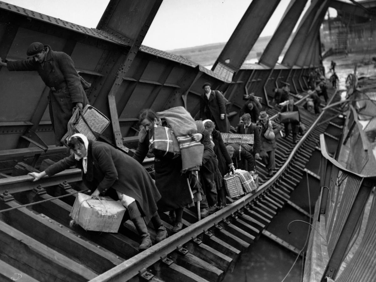 Kriegsflüchtlinge überqueren eine zerstörte Brücke über die Elbe.