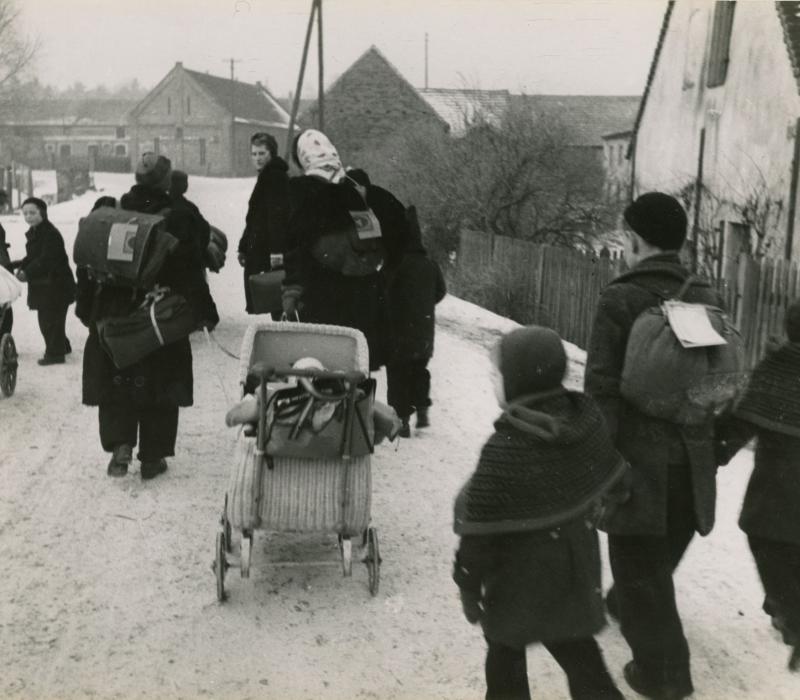 schwarz-weiß Aufnahme. Eine Gruppe von Menschen mit Kinderwägen läuft eine Straße entlang.