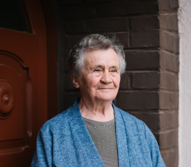 Portraitfoto einer älteren Frau mit blauer Strickjacke.