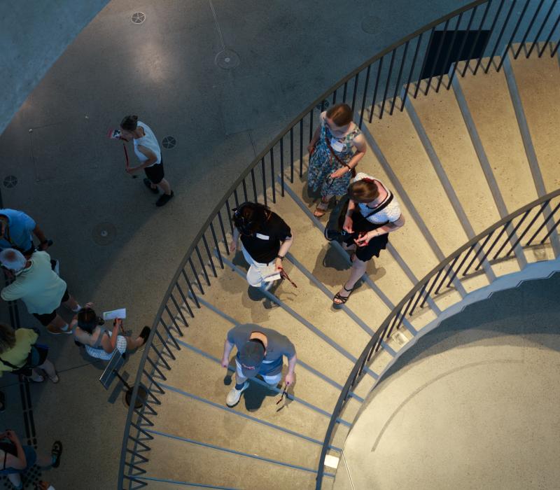 Vogelperspektive von oben auf die Treppe im Dokumentationszentrum. Vier Personen laufen gerade nach unten.