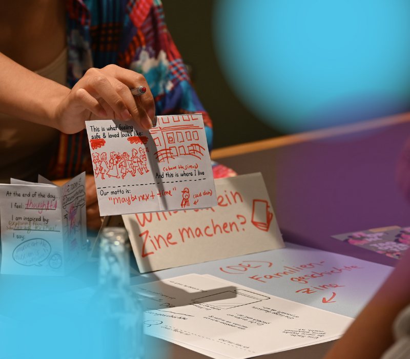 Nahaufnahme auf einen gezeichneten Comic mit roter Farbe, den eine Frau in der Hand hält.