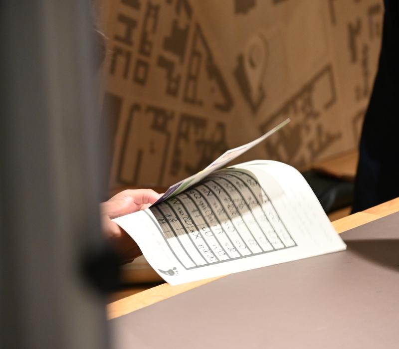 Nahaufnahme auf eine Hand, die einen Zettel mit Sütterlinschrift hält.