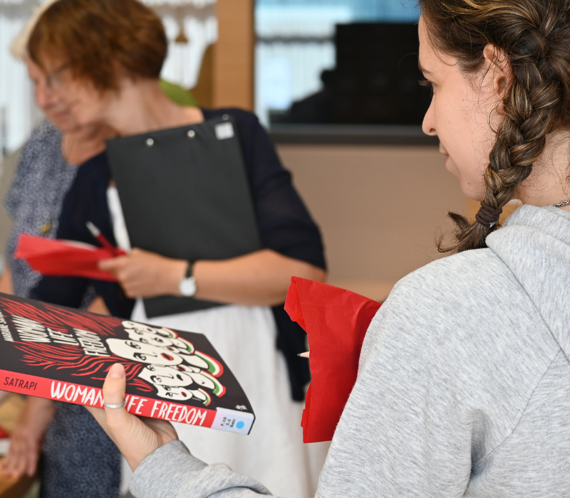 Eine junge Frau hält ein Buch in der Hand. Workshopsituation.