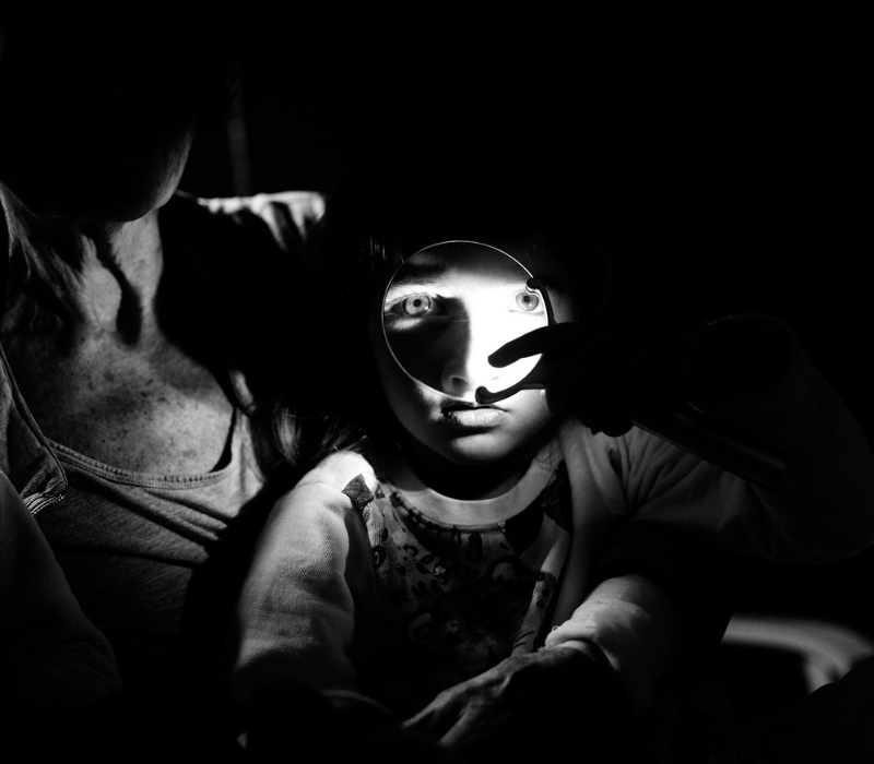 OSTGEBIETE / ZIEMIE ZACHODNIE. Eine deutsch-polnische Spurensuche Schwarz-weiß Aufnahme eines Kindes mit Lupe vor dem Gesicht.