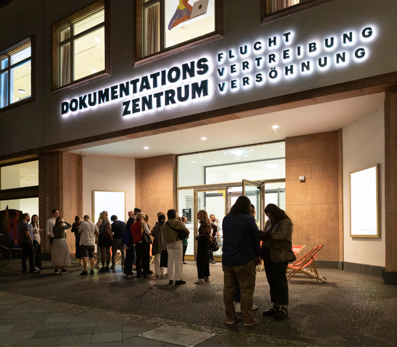Blick auf Eingang Dokumentationszentrum bei Nacht, mit Besuchenden