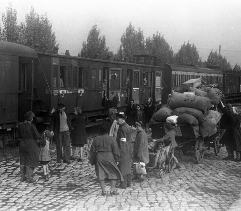 schwarz-weißes Bild, zeigt Menschen vor einem Zug